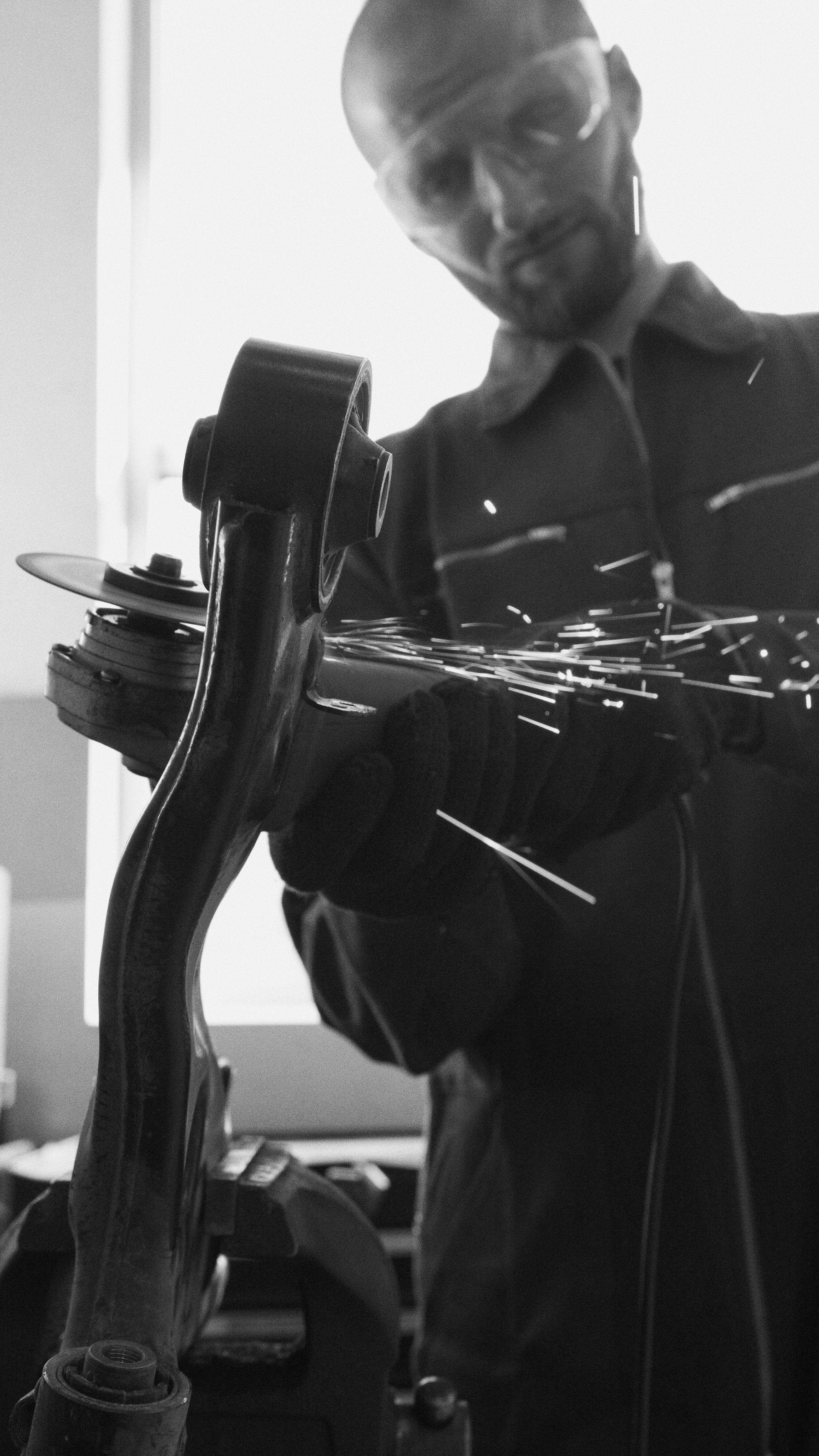 Mechanic grinding a car part, sparks flying