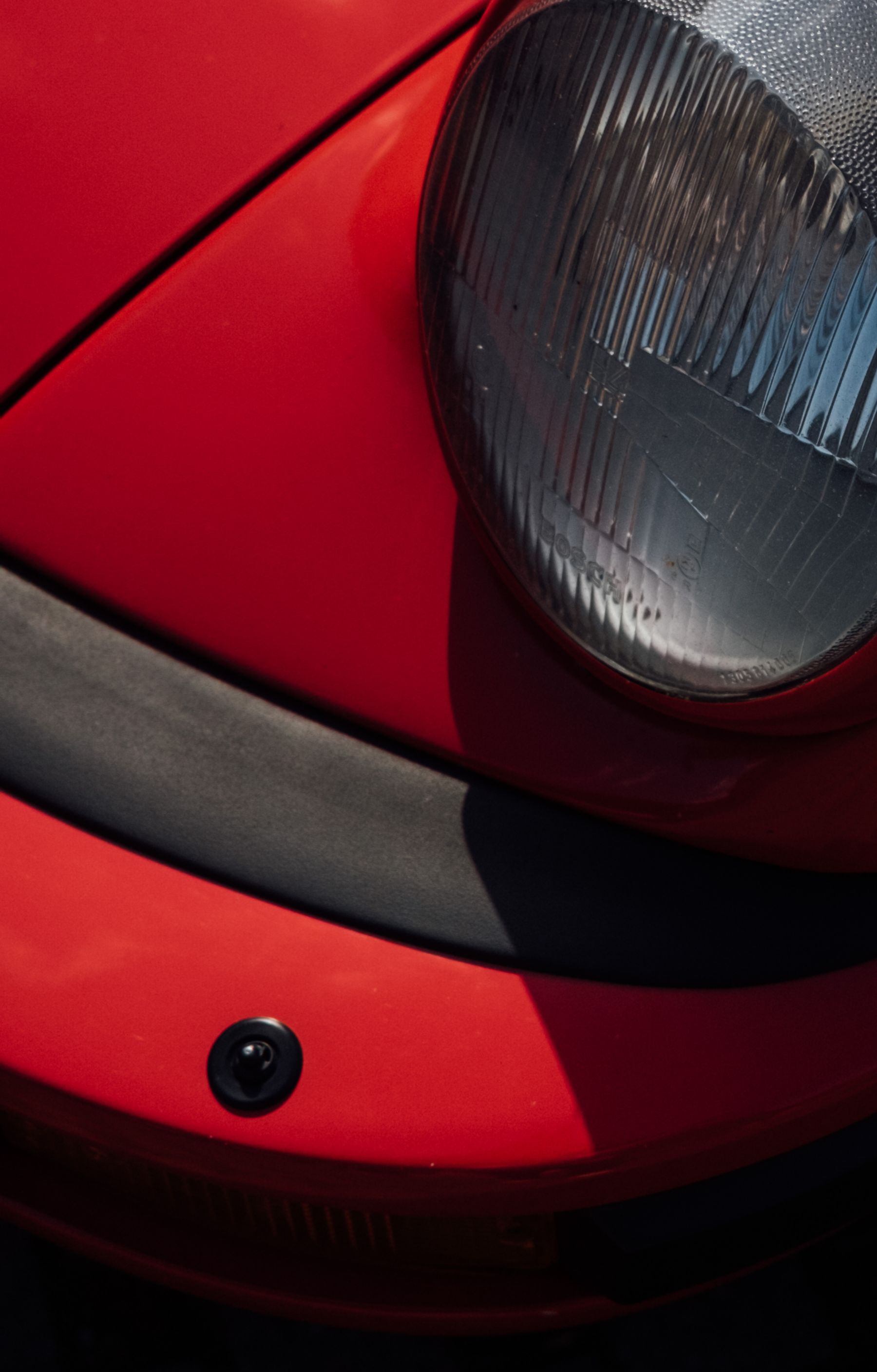 Close-up of a red car headlight and paintwork