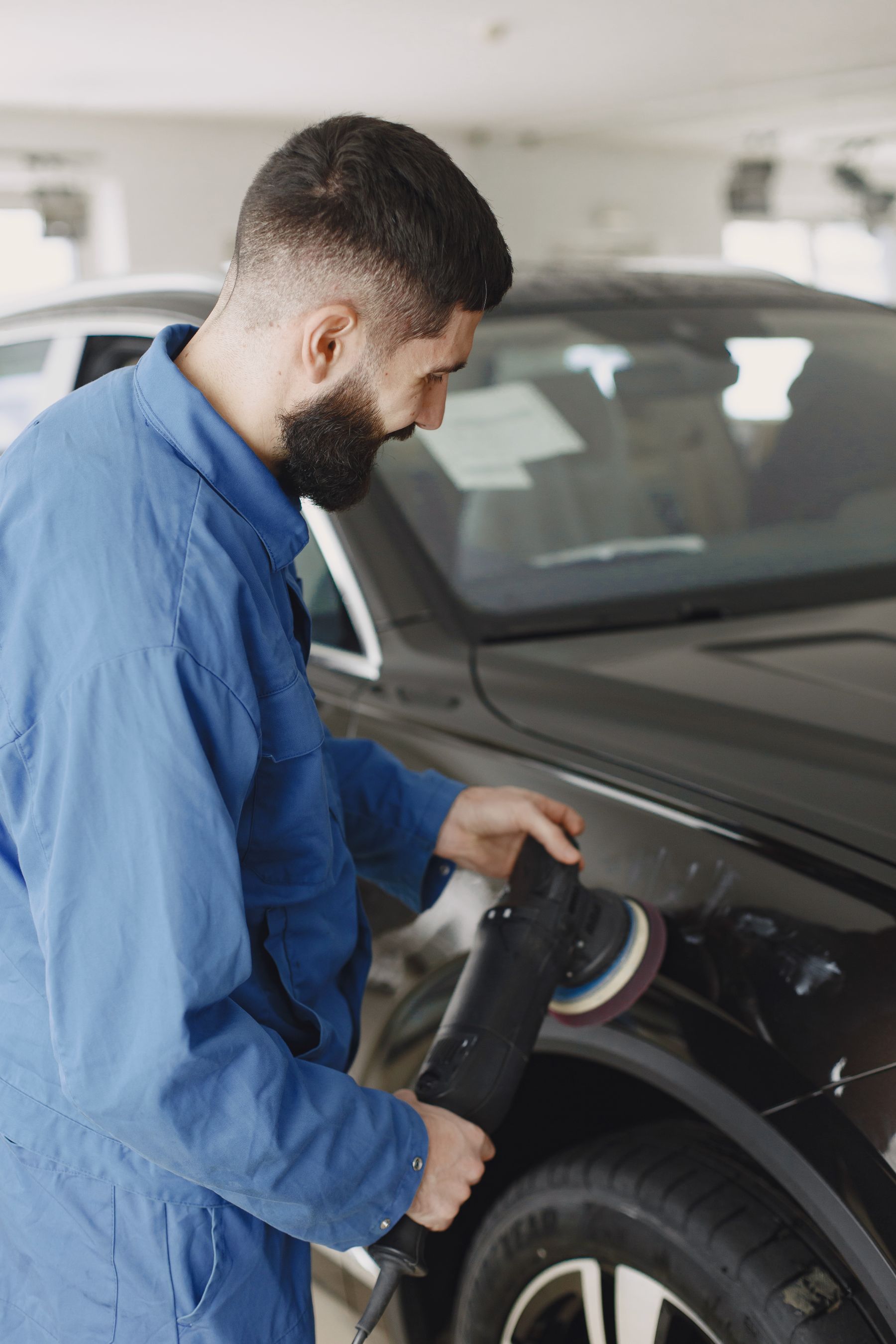 Mechanic in uniform polishing a car body