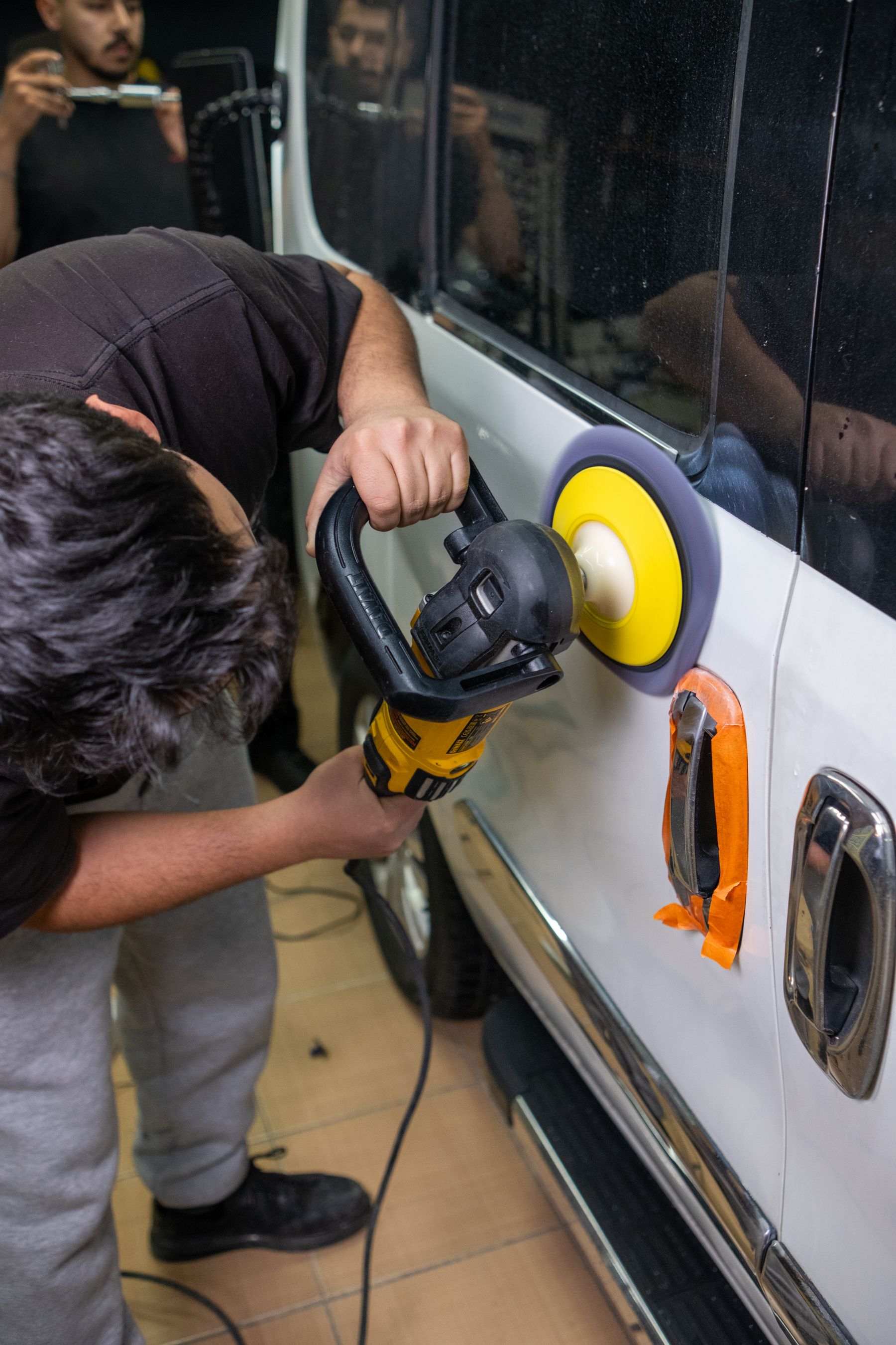 Technician machine-polishing a vehicle panel in the workshop